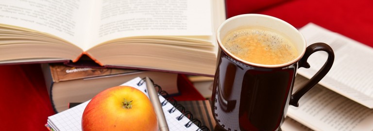Bücher, Kaffeetasse und Apfel