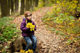 Junge im Wald mit Herbstblättern